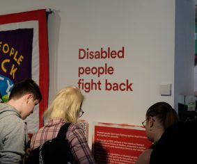 Three people reading large red text: 'Disabled people fight back'.