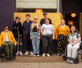 A group picture of the Access All Areas young producers with lead facilitator Helena Ascough and project assistant Maia.